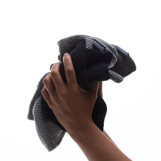 Person holding folded black cotton washcloth