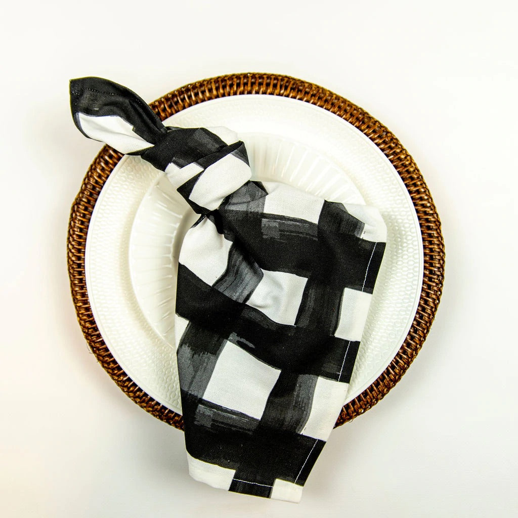 Sample of black and white napkin tied in a knot on top of a white plate and a gold placement