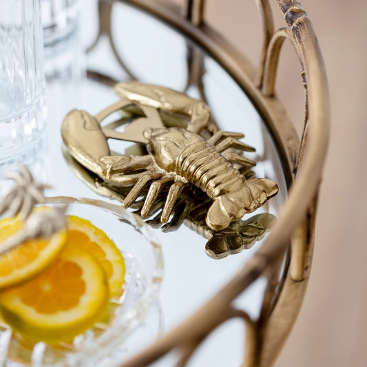 Gold lobster bottle opener placed on mirrored coffee table