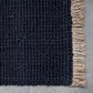 Close up image of black woven floor mat with straw coloured fringe detail