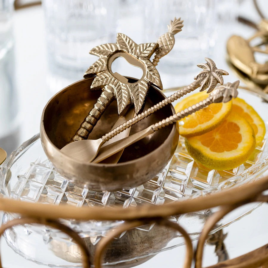 Brass cheeseboard spreader knives in a brass bowl with orange slices