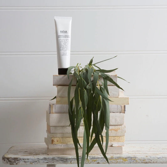 Handcream displayed on pile of books with eucalyptus leaves