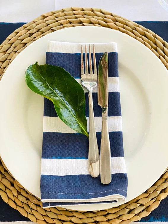 Striped navy and white napkin on white plates with woven placemat