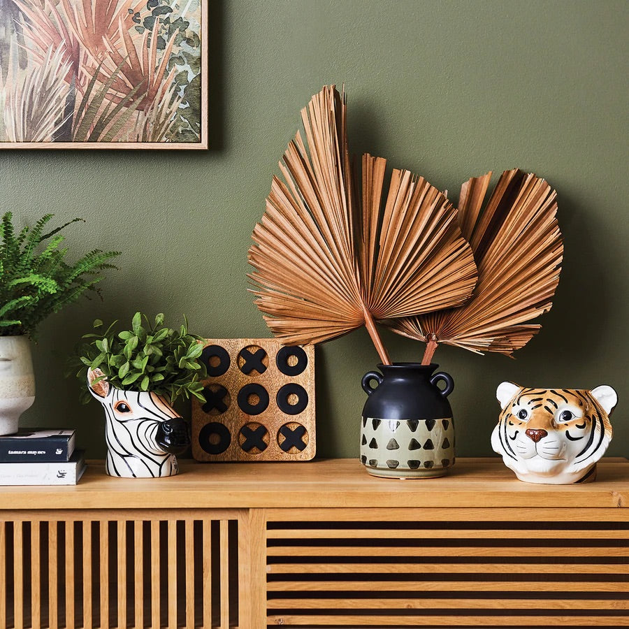 Side cabinet decorated with clay pots and animal shaped vases with a sage green wall