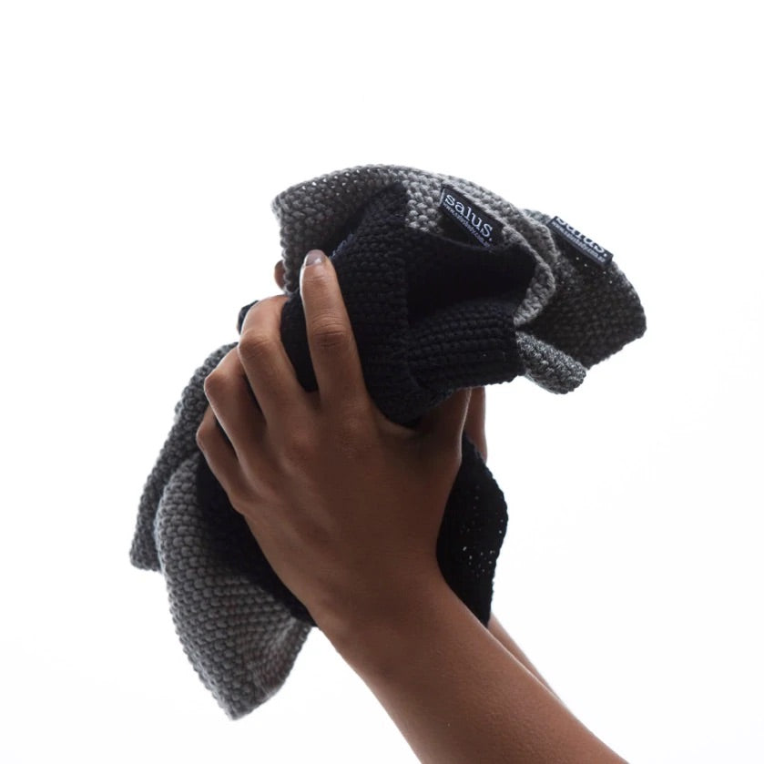 Person holding folded black cotton washcloth