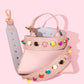 Pink bag strap with multi-coloured studs on pink bag.