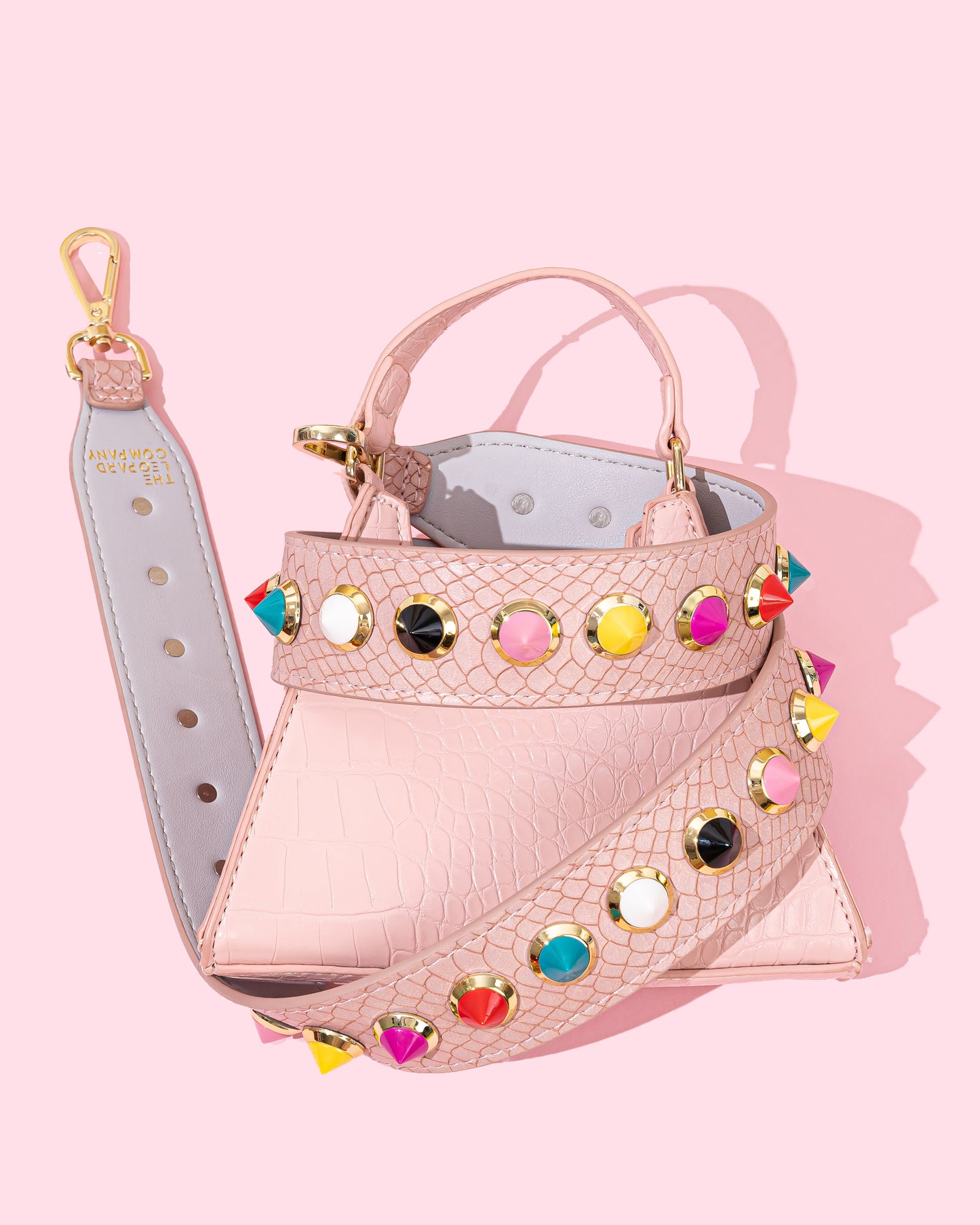 Pink bag strap with multi-coloured studs on pink bag.